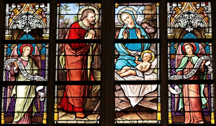 Vibrant stained glass window illustrating a biblical nativity scene with vivid colors in a church setting.