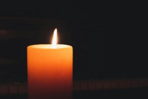 Close-up of a glowing candle in the dark, highlighting warmth and serenity.