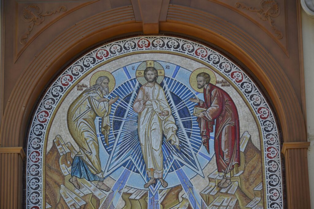 Intricate religious mosaic art depicting three figures in a church setting.