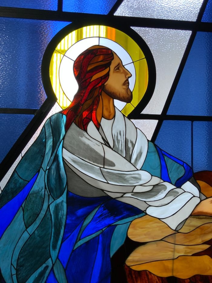 Vibrant stained glass depiction of Jesus Christ with halo, highlighting spirituality and artistry.