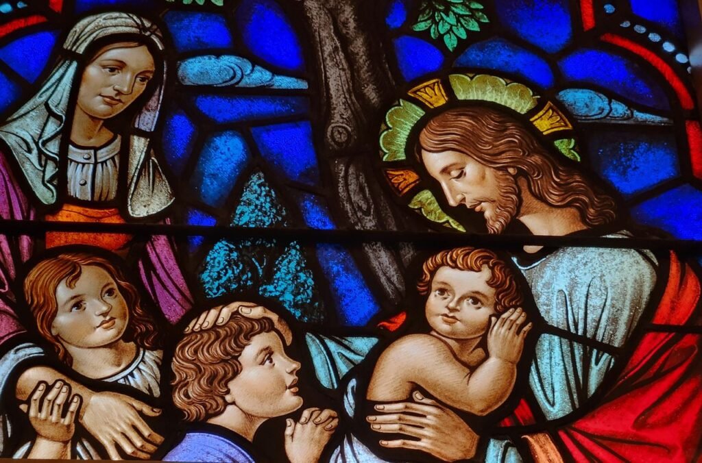 Colorful stained glass window showing Jesus with children in a religious setting.